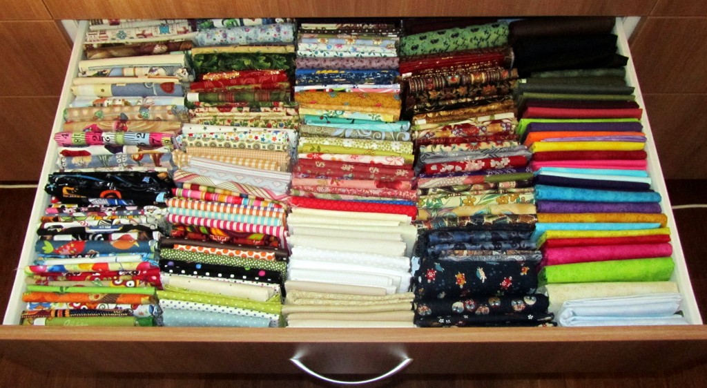 A drawer full of neatly folded fabrics.
